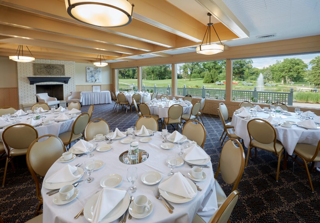 Elegant events room with tables fully set and views of the garden.