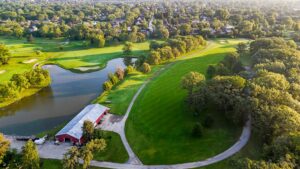 Aerial view of a green and surrounding water and trees.
