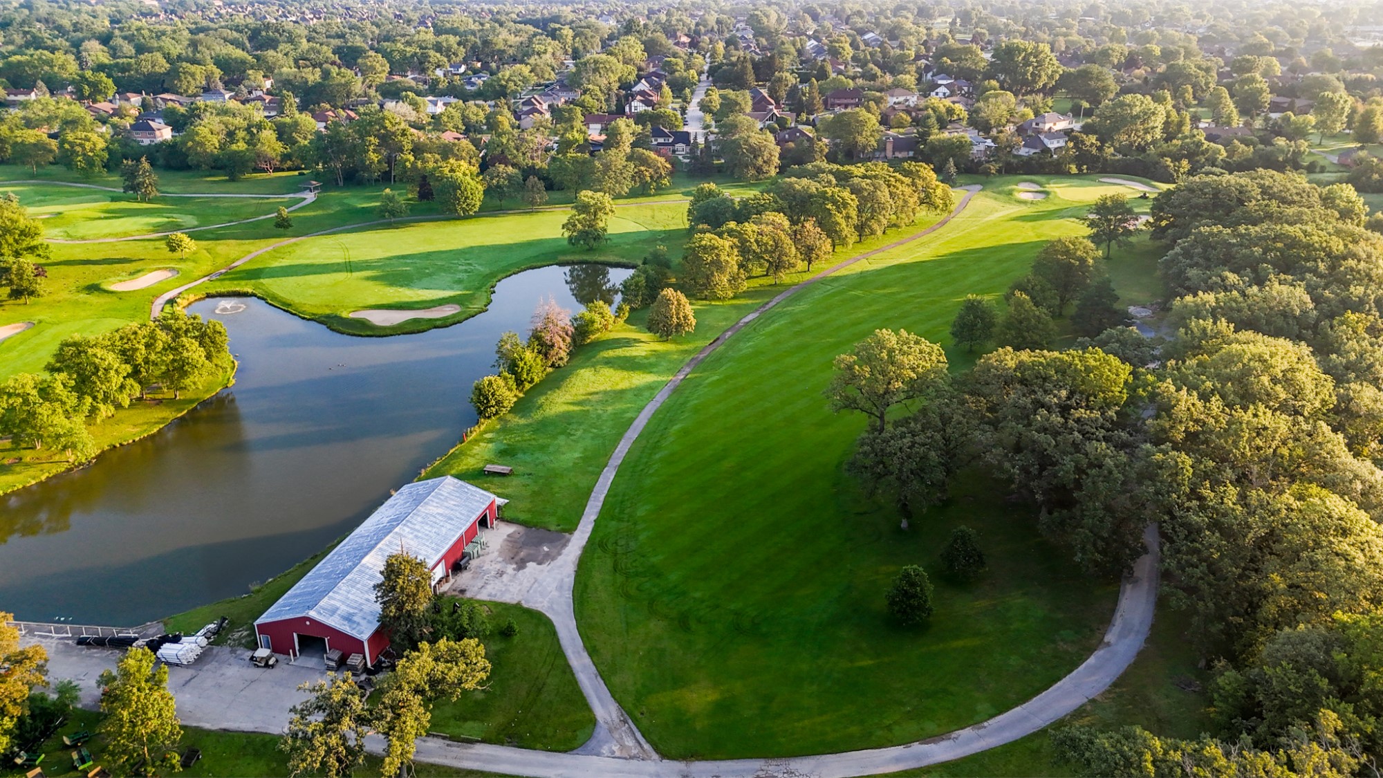 Aerial view of a green and surrounding water and trees.