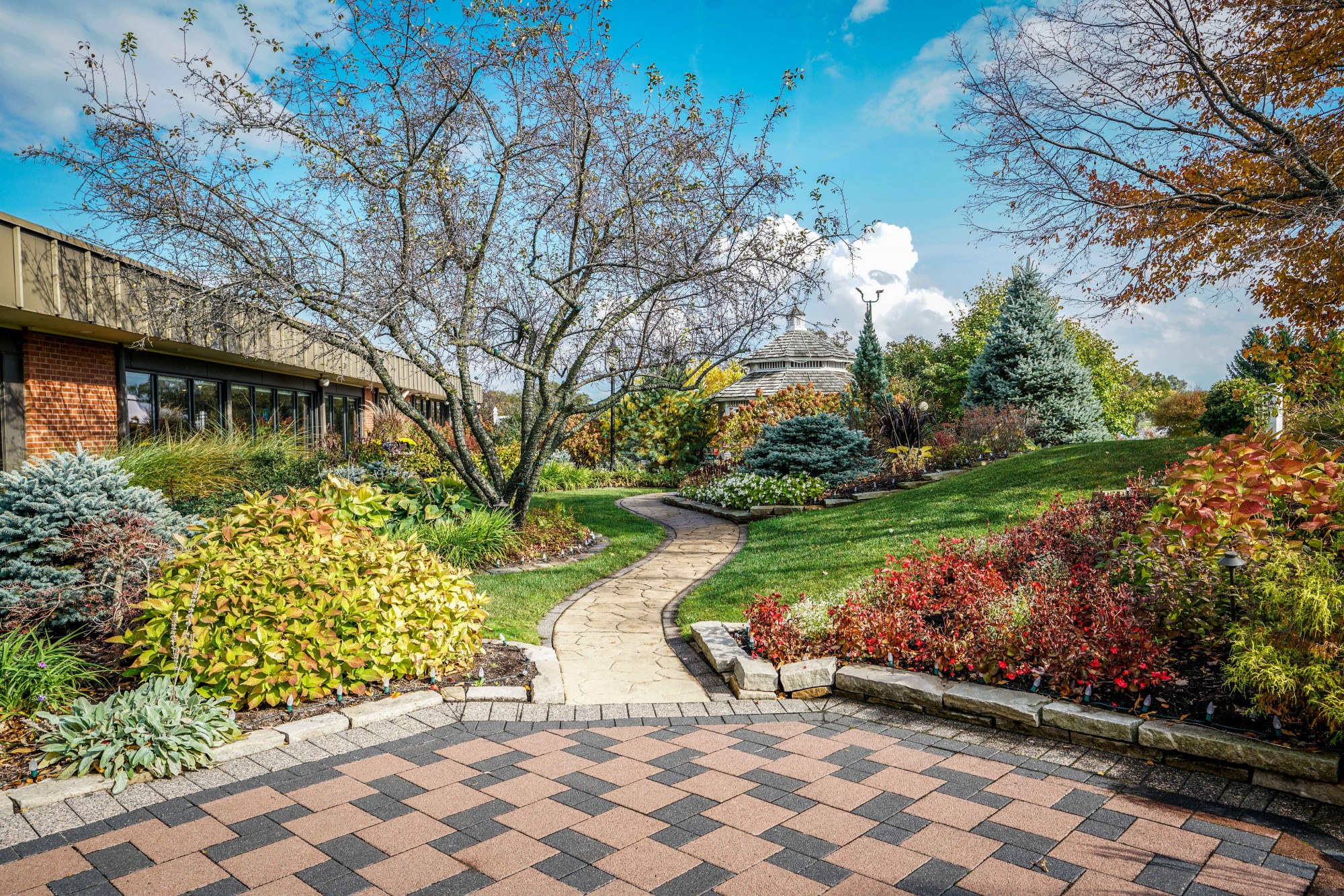 A lush garden with stone path leading to a gazebo.
