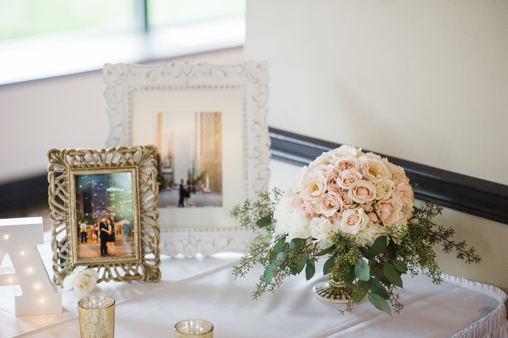 Wedding display table with elegant picture frames and bouquet.
